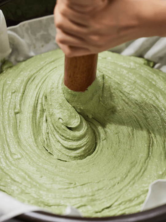 Large vat of Arencia Fresh Green Mochi Rice Cleanser being stirred with a wooden stick.