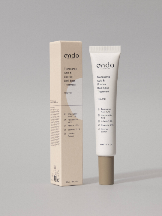 Tube of Ondo Beauty's Tranexamic Acid & Licorice Dark Spot Treatment standing next to its box against a light grey background. Available at Sinless Skincare.