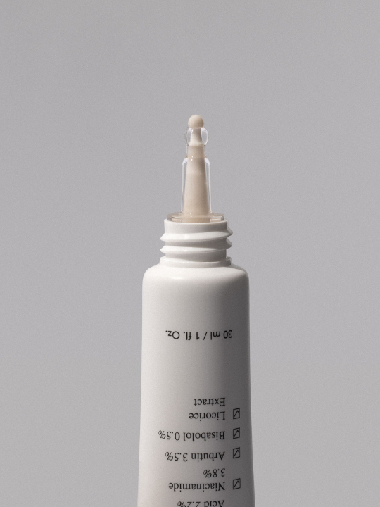 Ondo Beauty's Tranexamic Acid & Licorice Dark Spot Treatment uncapped with a drop squeezed out, against a grey background.