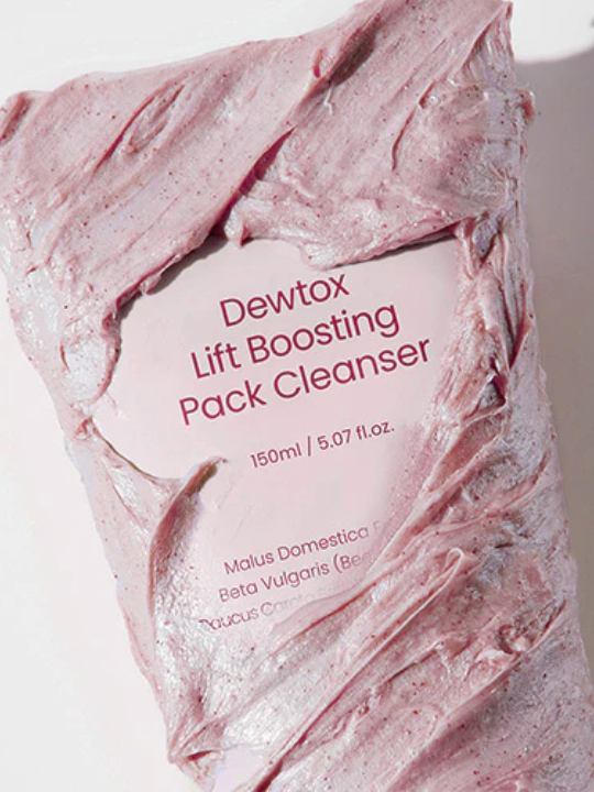 Close up tube of 'Dewtox Lift Boosting Pack Cleanser' covered in pink cream.