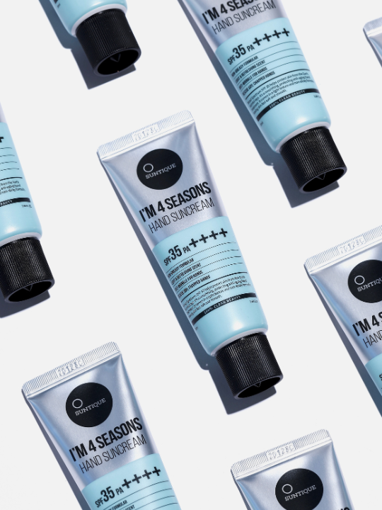 Several tubes of Suntique's I'm 4 Seasons Sun Hand Cream lying down in rows, face up, against a white background.