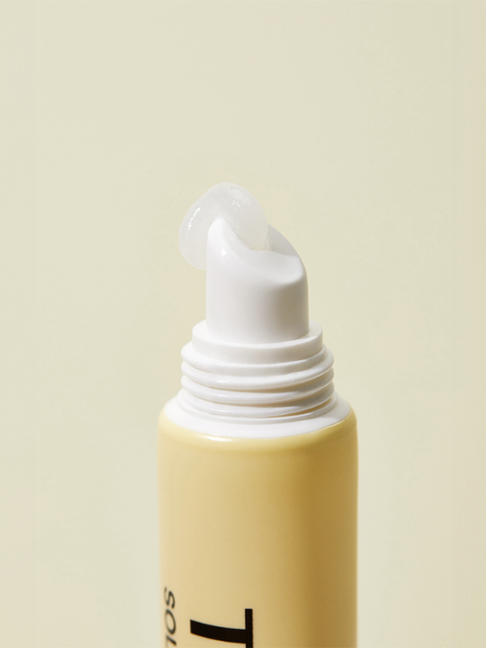 Close up of an uncapped Torriden Solid In Lip Essence with some product being squeezed from the top, against a pale yellow background. Available at Sinless Skincare.