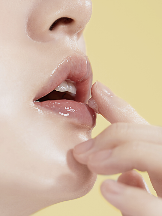 Close up of woman's lips and fingers applying Torridens Solid In Lip Essence