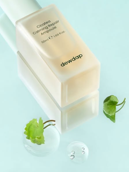 Dewdrop Cicatea Calming Repair ampoule bottle with green centella leaves on a light blue surface dotted with small drops of serum.