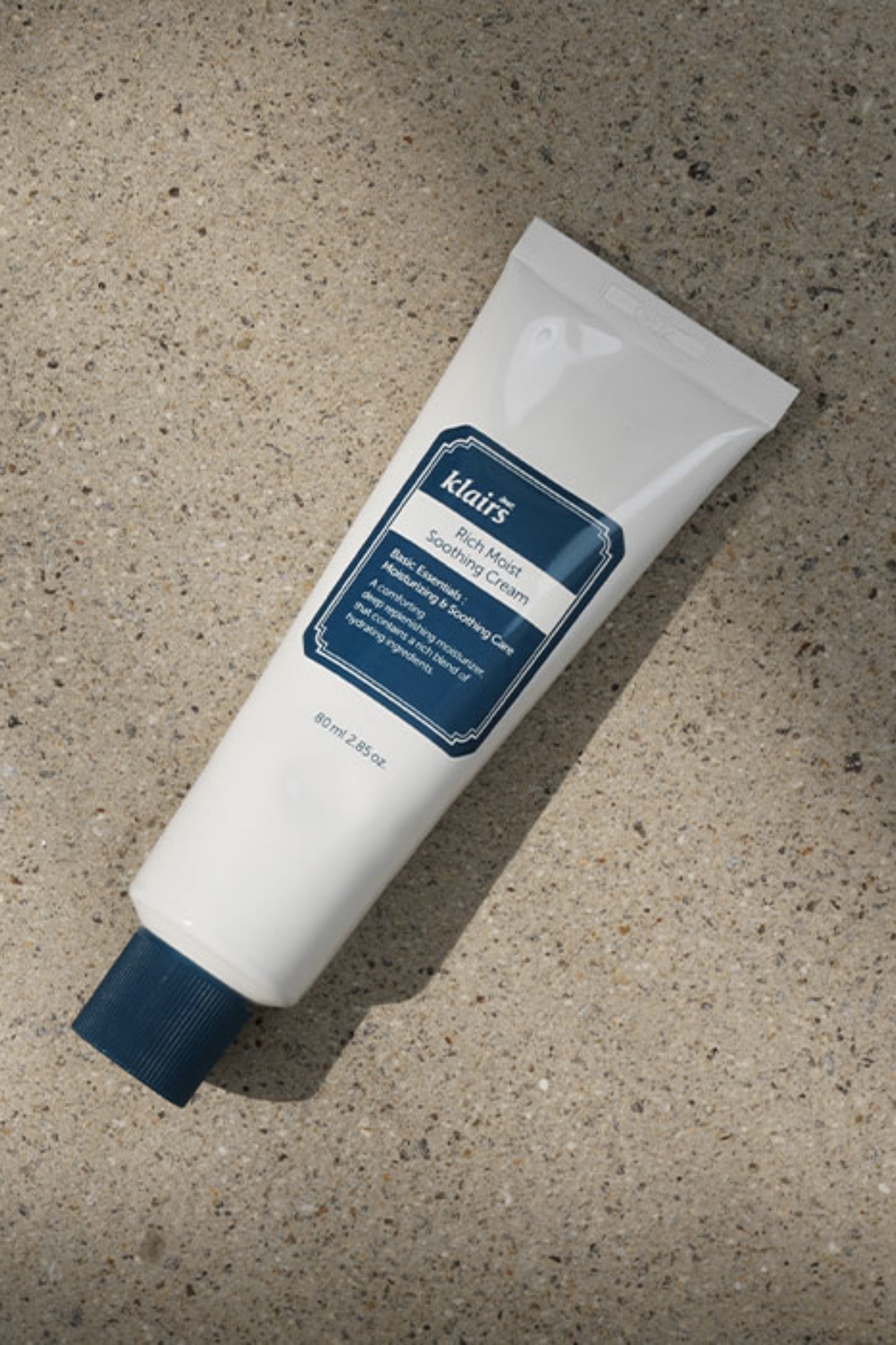 Klairs' Rich Moist Soothing Cream lying on concrete, view from above.