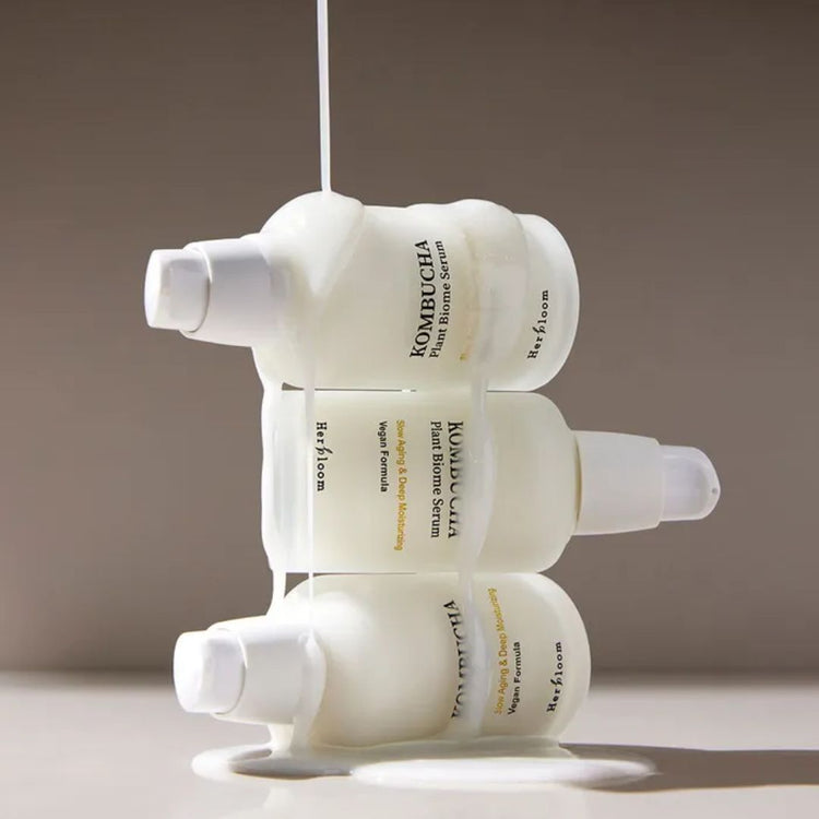 Three stacked bottles of Herbloom Kombucha Plant Biome Serum against a taupe background