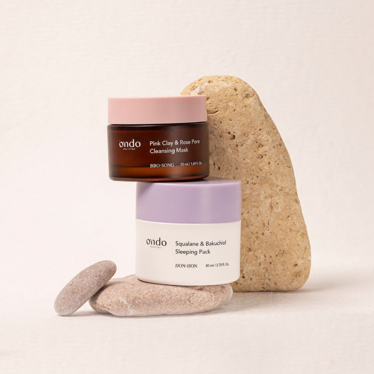 Ondo Beauty 36.5 Pink Clay Rose Pore Clarifying Mask and Squalane Bakuchiol Sleeping Pack sitting on stones on a neutral background