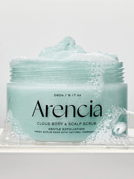 A jar of Arencia Cloud Body & Scalp Scrub French Mint & Lily  with light aqua scrub visible at the open top and around the base,, surrounded by bubbles, photographed on a clean white background.