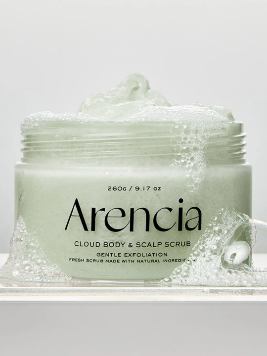 Open jar of Arencia Cloud Body & Scalp Scrub surrounded by bubbles on a light grey background. Available at Sinless Skincare.