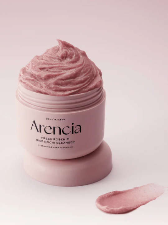 Open jar of Arenicia Rosehip Rice Mochi Cleanser on a light pink background. Available at Sinless Skincare.
