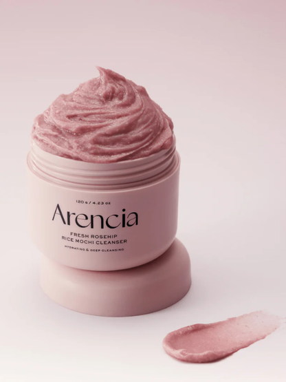 Open jar of Arenicia Rosehip Rice Mochi Cleanser on a light pink background. Available at Sinless Skincare.