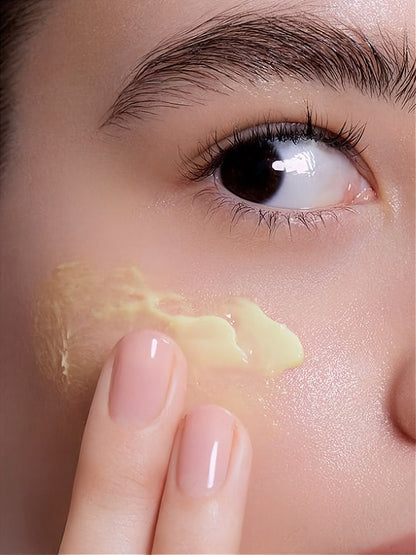 Close-up of a person applying cream under their eye with a finger.