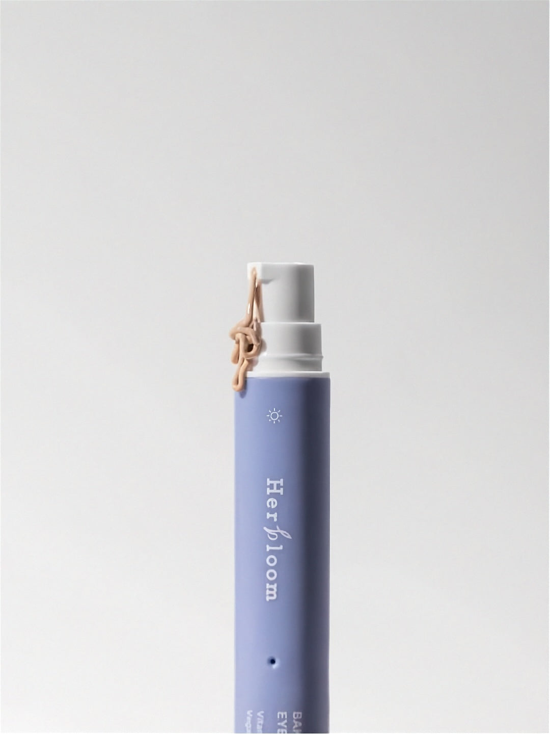 Tube of Herbloom Bakuchiol Dual Vita Eye Cream with tinted cream being pumped out on a white background.