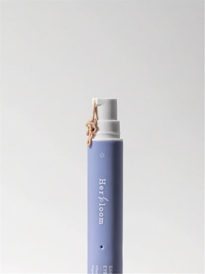 Tube of Herbloom Bakuchiol Dual Vita Eye Cream with tinted cream being pumped out on a white background.