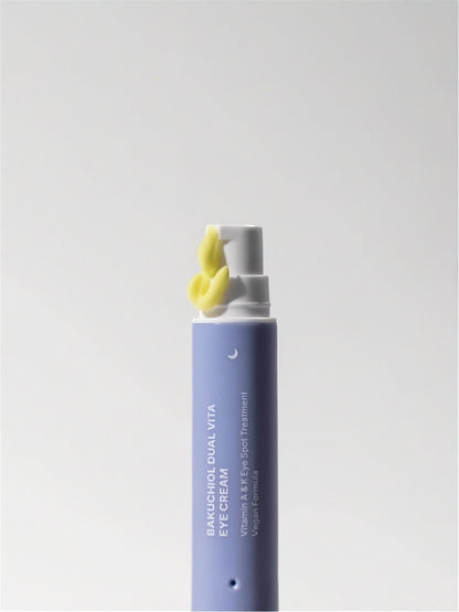 Tube of Herbloom Bakuchiol Dual Vita Eye Cream with yellow cream being pumped out on a white background.