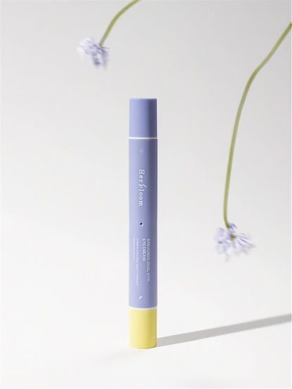 Purple and yellow tube of tube of Herbloom Bakuchiol Dual Vita Eye Cream on a light gray background with floral elements.