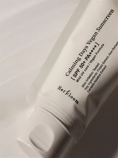 Close up of Herbloom Calming Days Vegan Sunscreen SPF 50+ tube in low light on a white background