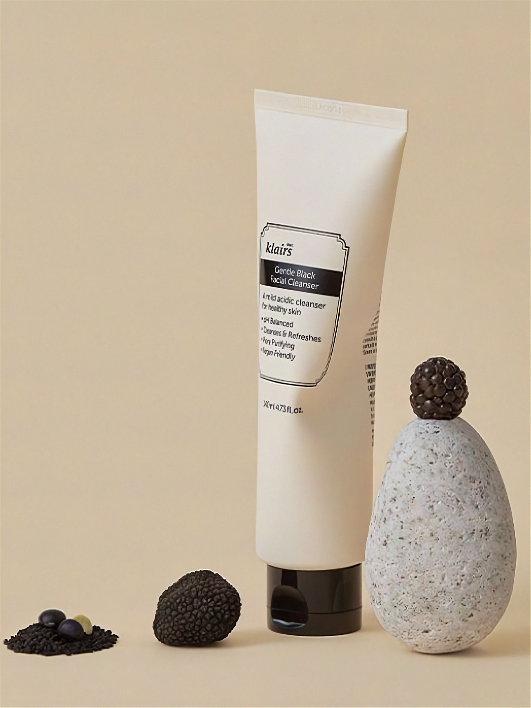 Klairs Gentle Black Facial Cleanser tube with decorative stones and a stone-like container on a beige background