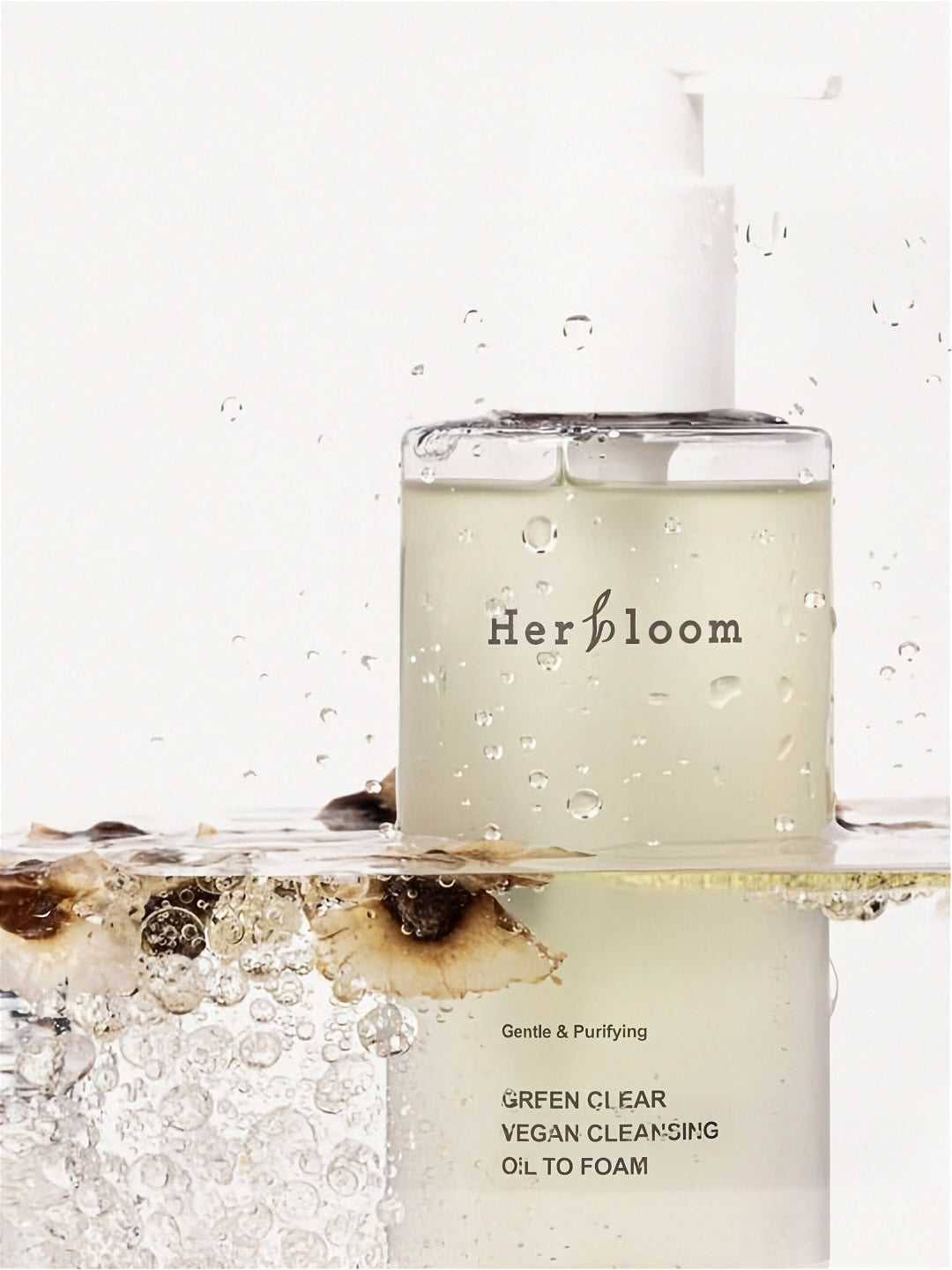 Herbloom Green Clear Cleansing Oil to Foam bottle submerged in clear water with botanical elements against a white background