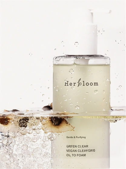 Herbloom Green Clear Cleansing Oil to Foam bottle submerged in clear water with botanical elements against a white background