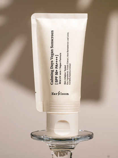 Herbloom Calming Days Vegan Sunscreen on a glass pedestal, with a shadow on the beige background.