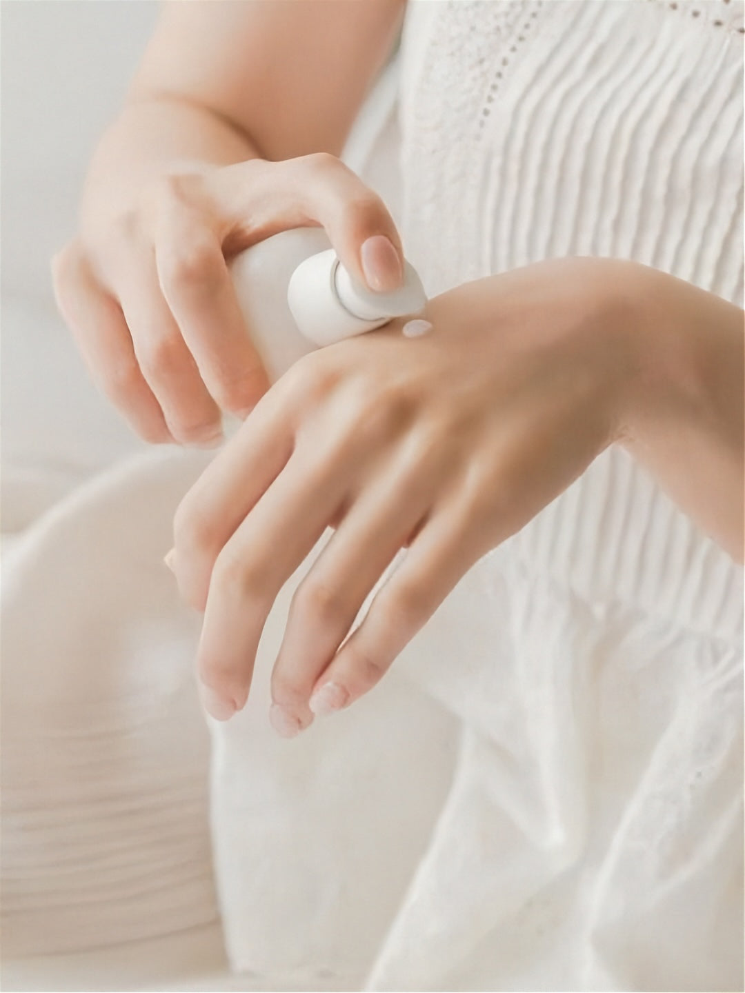 Person in white dress applying Herbloom's Kombucha Plant Biome Serum  to their hand against a neutral background