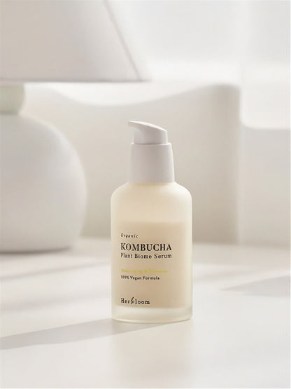 Bottle of Herbloom Kombucha Plant Biome Serum on a neutral surface with white lamp in background