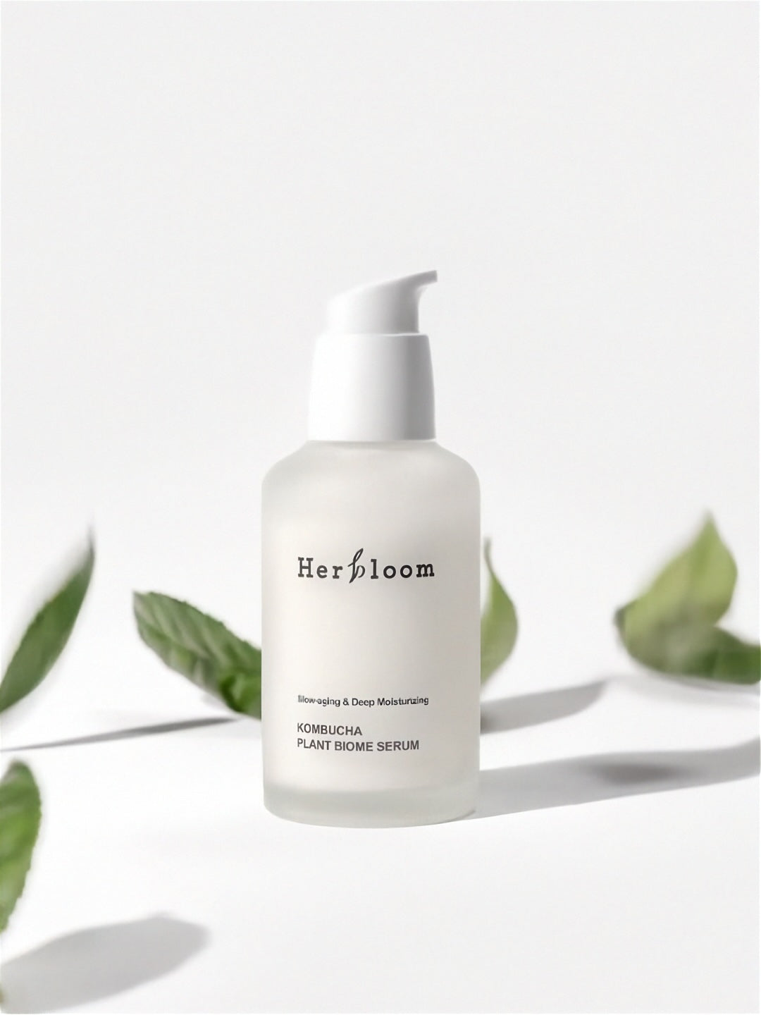 Herbloom Kombucha Plant Biome Serum with green leaves on a white background