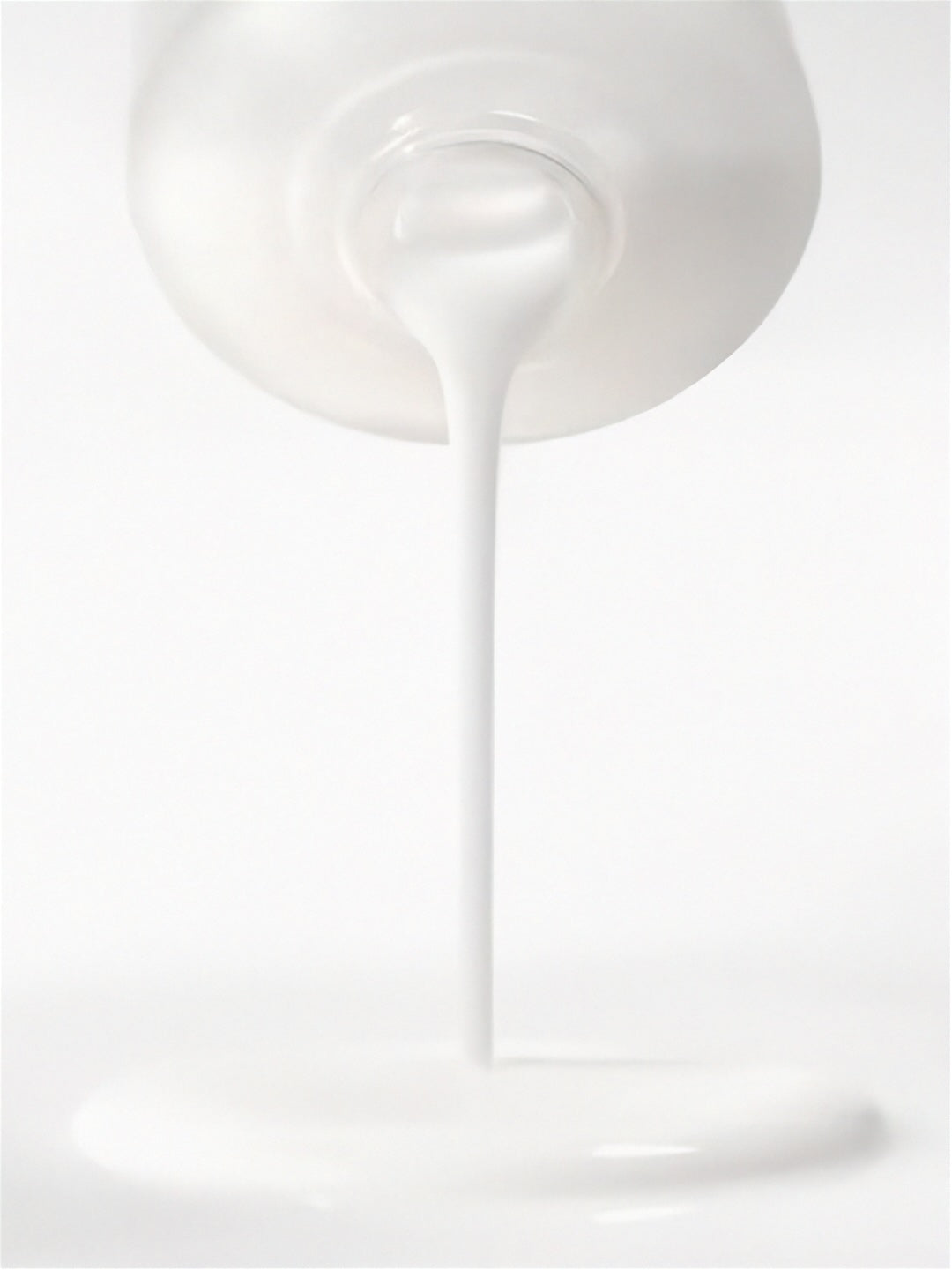 White liquid being poured from a container on a white background