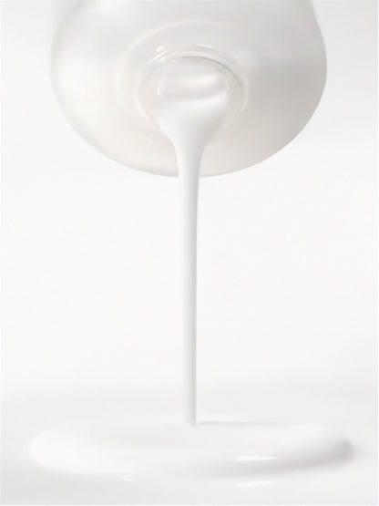 White liquid being poured from a container on a white background