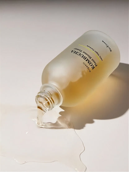 Herbloom Kombucha Plant Biome Toner bottle tipped over with liquid pouring out on a neutral grey surface