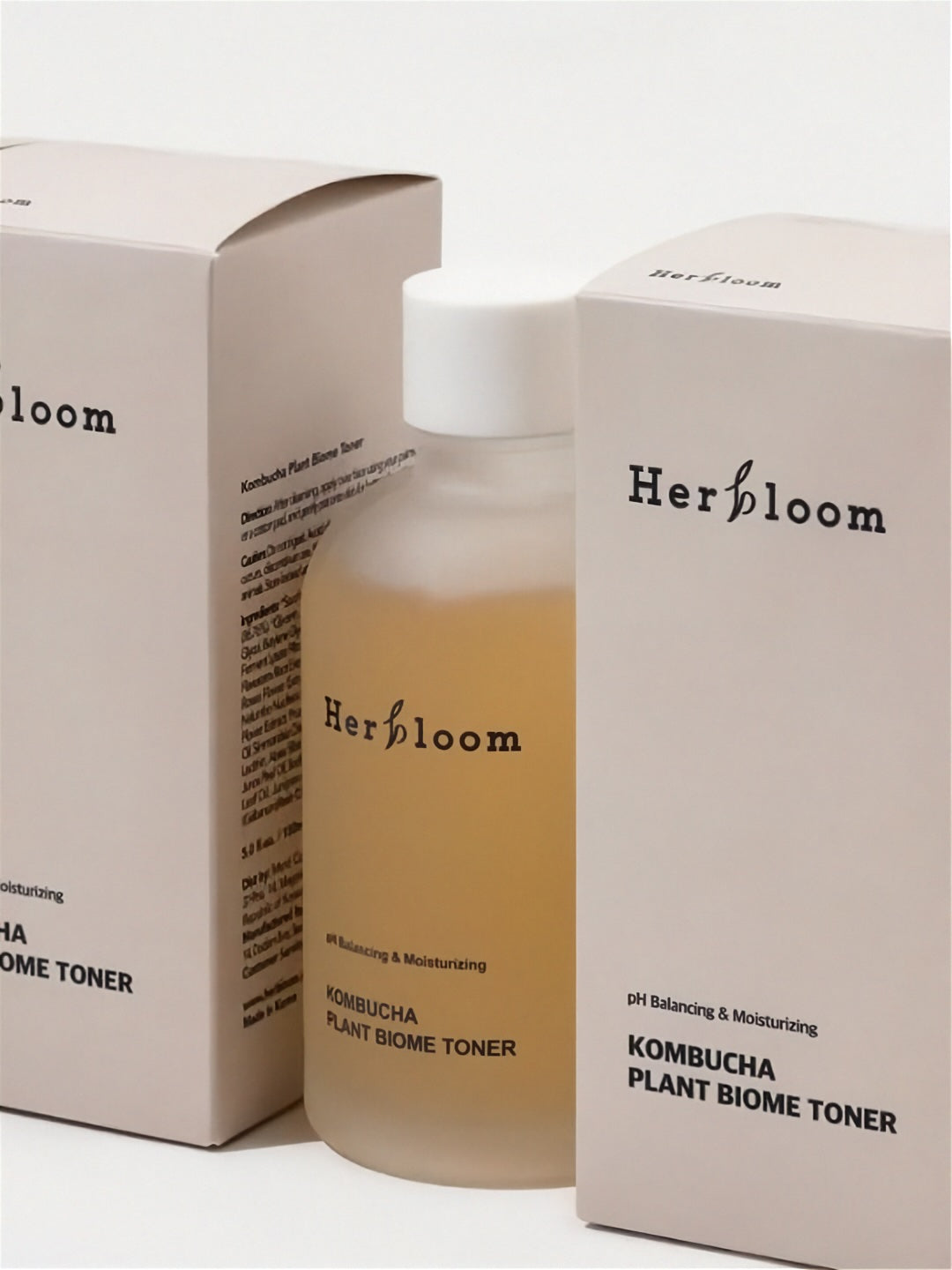 Herbloom Kombucha Plant Biome Toner bottle standing between two retail boxes on a white background