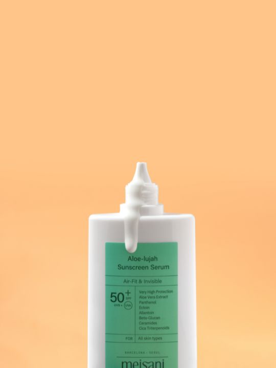 Open tube of Meisani Aloe-lujah Sunscreen Serum on a light orange background