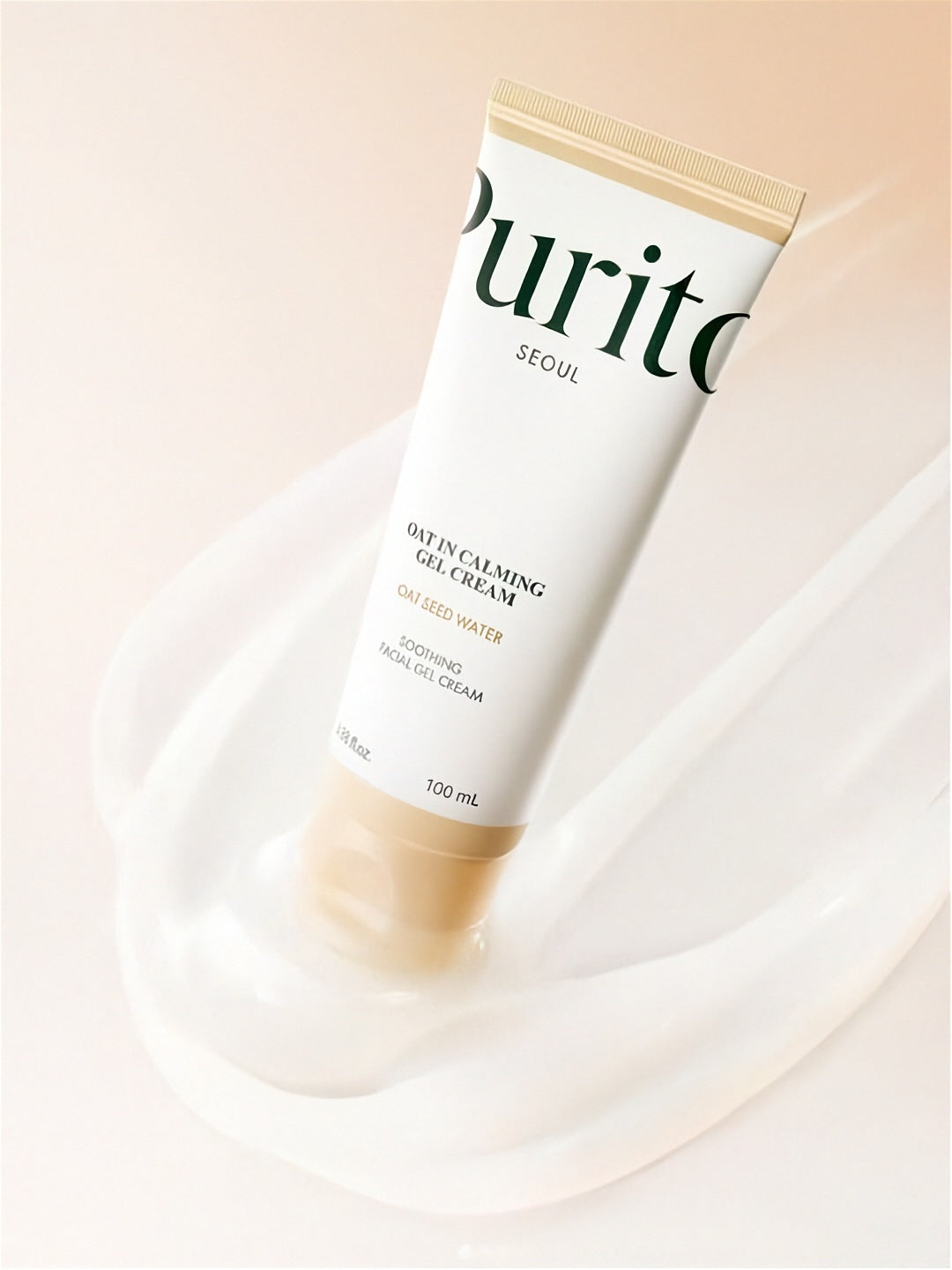Tube of Purito Oat In Calming Gel Cream standing on large swatch of clear gel, on a gradient beige background