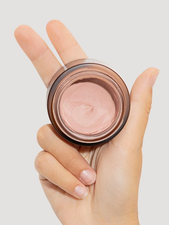 Hand holding an open jar of Ondo Beauty Pink Clay & Rose Pore Mask on a light grey background