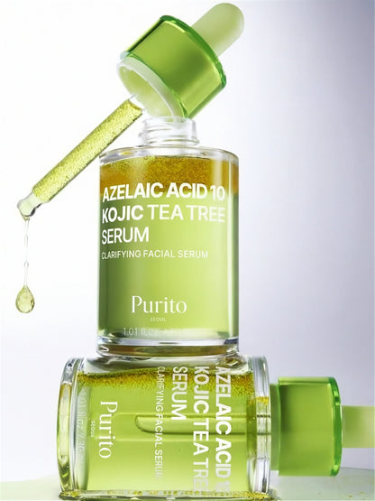 One bottle of Purito Seoul Azelaic Acid 10 Kojic Tea Tree Serum standing with its dropper out on top of another bottle of serum, against a light grey background,.