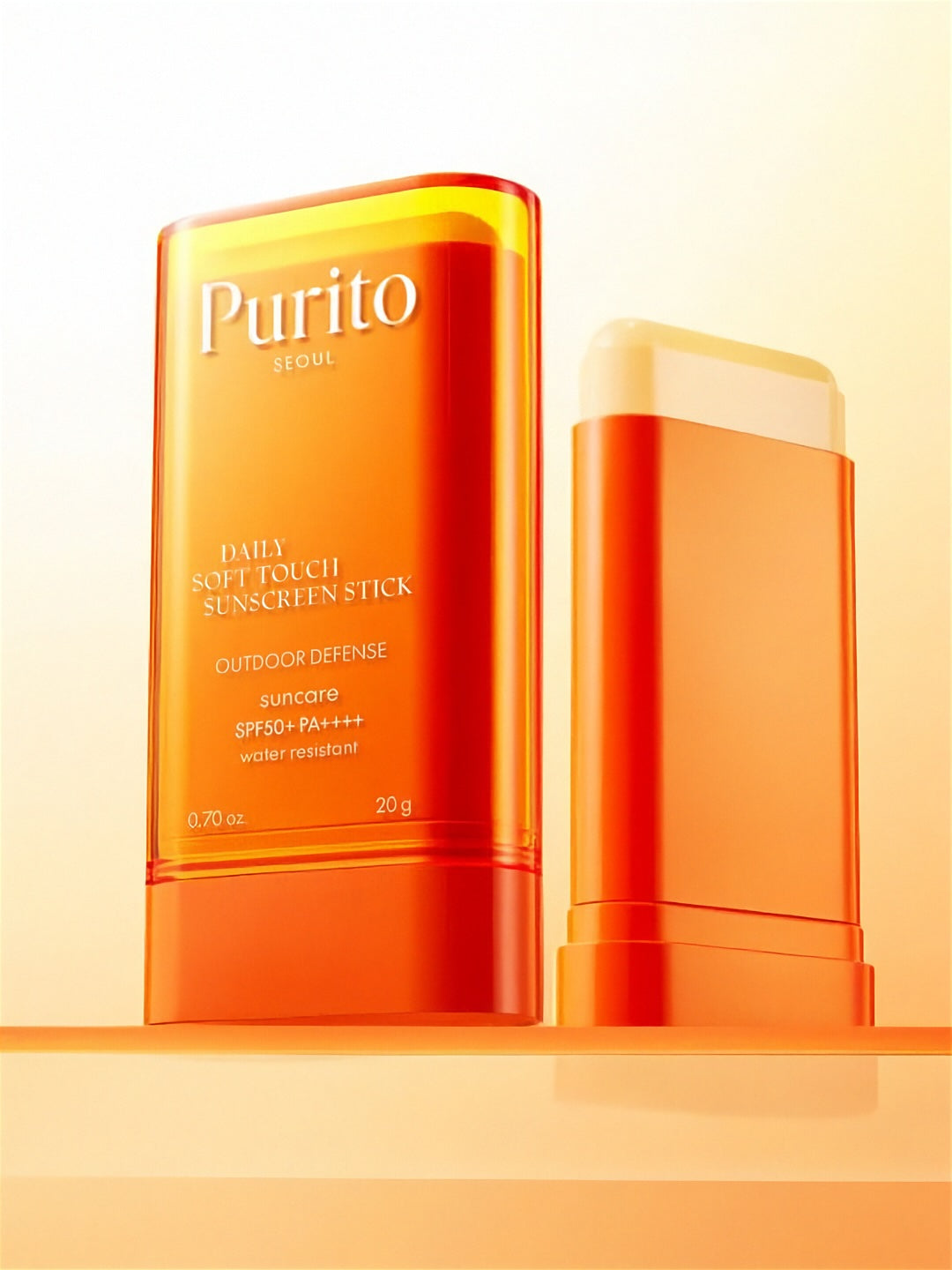Two tubes of Purito Seoul Daily Soft Touch Sunscreen Stick with one cap off, on a light orange background
