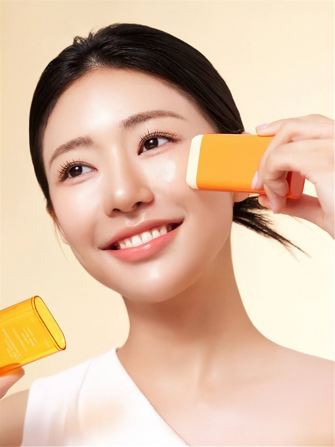 Woman applying Purito Seoul Daily Soft Touch Sunscreen Stick to her cheek on a light yellow background