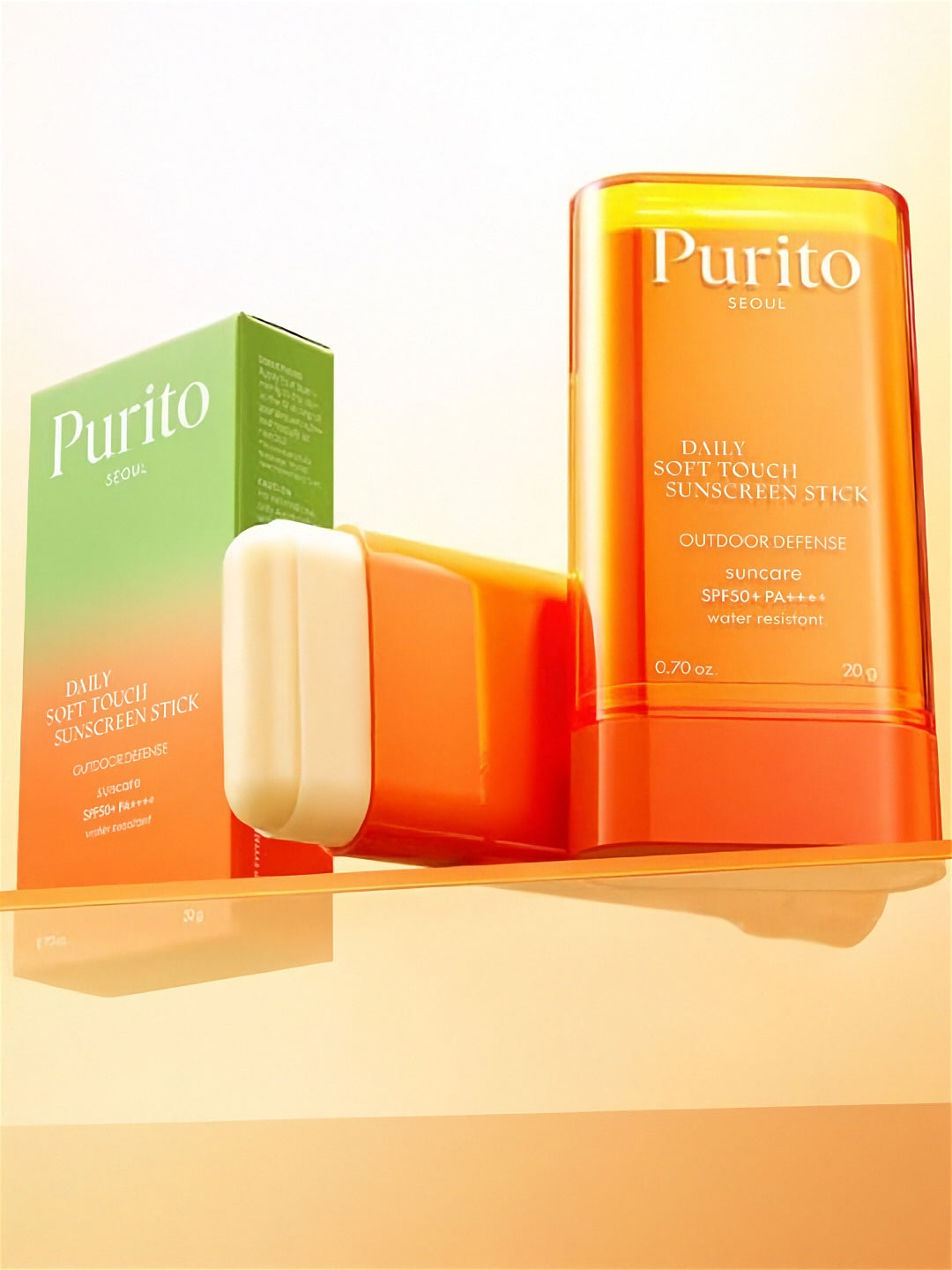Two tubes of Purito Seoul Daily Soft Touch Sunscreen Stick, one on its side without a cap, next to its retail box