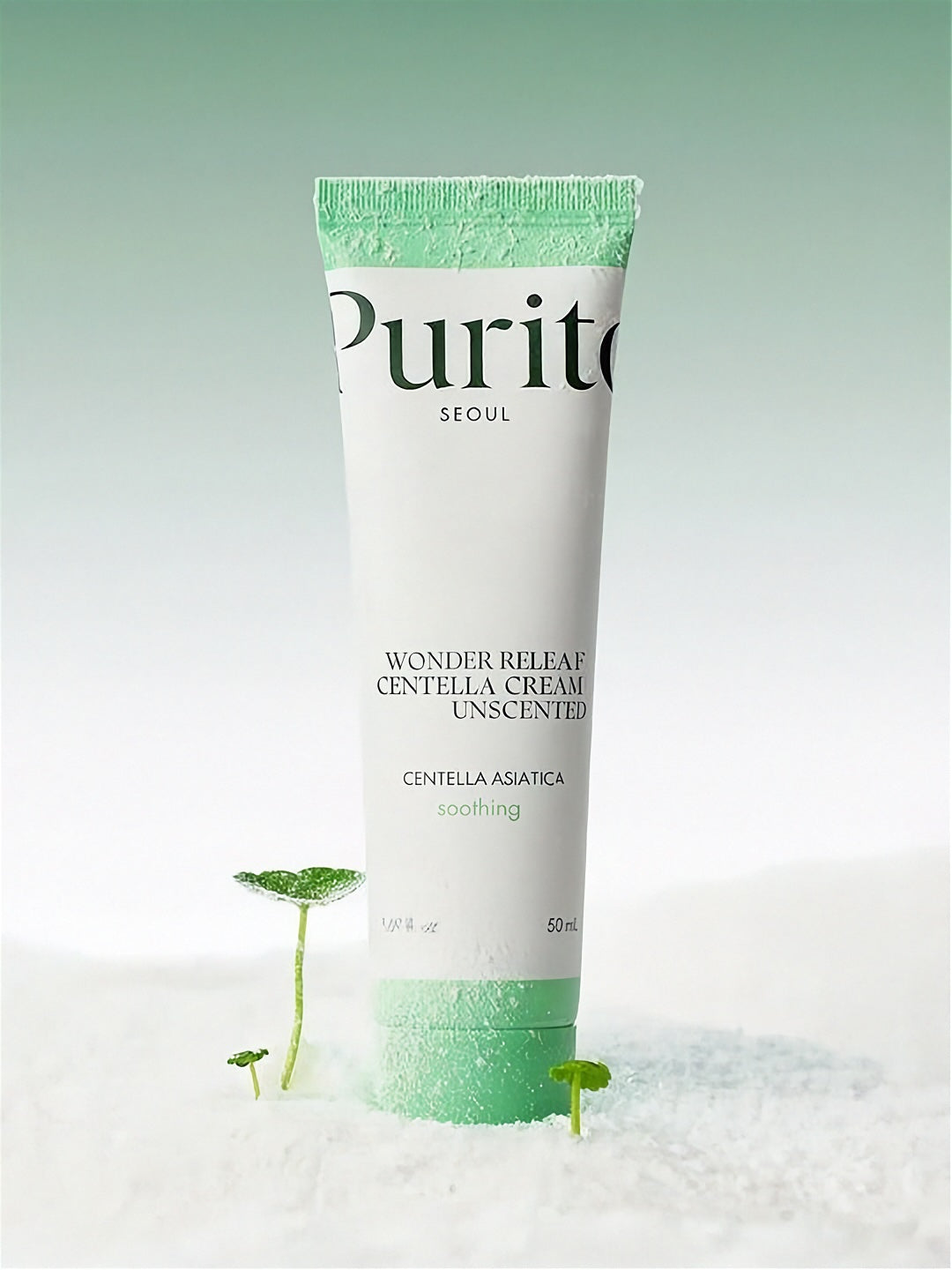 Tube of Purito Wonder Releaf Centella Unscented Cream standing on white powder with small cica plants, against a light gradient green background