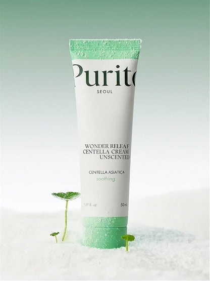Tube of Purito Wonder Releaf Centella Unscented Cream standing on white powder with small cica plants, against a light gradient green background