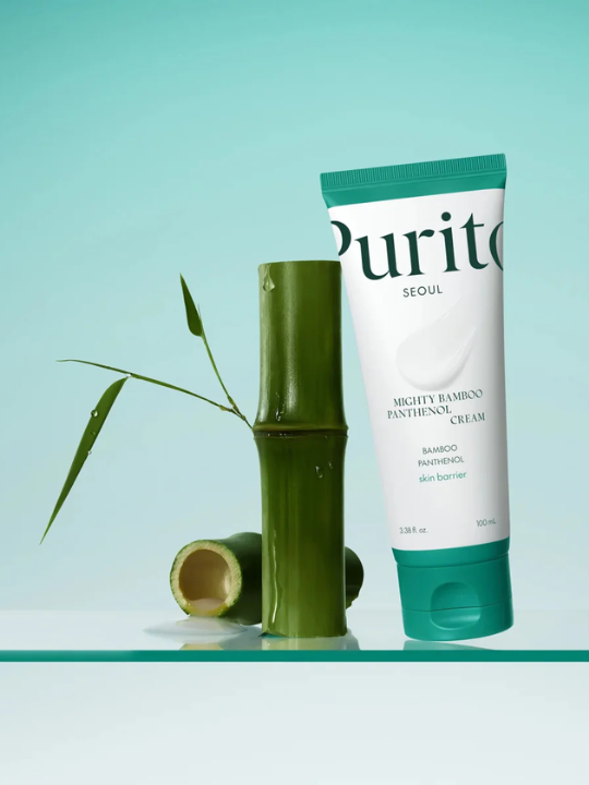Tube of Purito Mighty Bamboo Panthenol Cream standing next to a stick of bamboo, against a light green background.