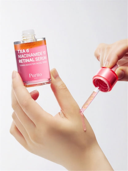 Hand applying Purito Seoul TXA 6 Niacinamide 10 Retinal Serum with a dropper on their other hand against a light grey background
