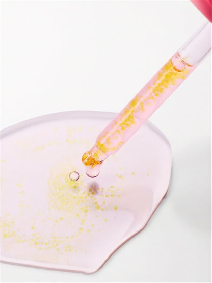 Close up of dropper from Purito Seoul TXA 6 Niacinamide 10 Retinal Serum with a light pink puddle of serum showing the encapsulated retinal beads, on a white background