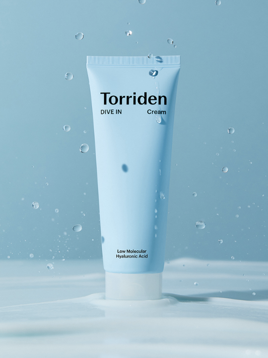 Tube of Torriden's Dive In Hyaluronic Acid Cream against a blue background and drops of water falling down. Available at Sinless Skincare.
