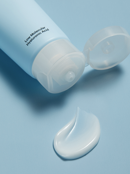 Torriden Dive In Hyaluronic Acid Cream lying on a blue surface with the cap open and white cream squeezed out.