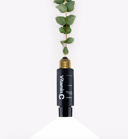 Open bottle of Vegreen's Intensive Vitamin C 20% Ampoule with green leaves sprouting from the top, on a white background. Available at Sinless Skincare.