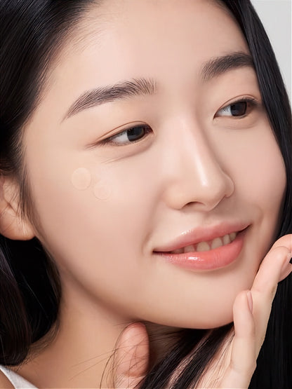 Close-up of a woman wearing two transparent Purito Wonder Releaf Centella Spot Patches on her cheek