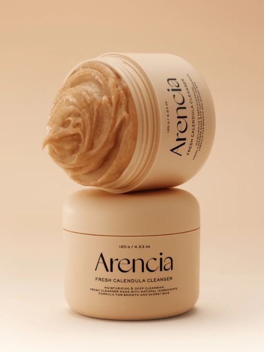 Two jars of Arencia Calendula Rice Mochi Cleanser on a beige background with one jar open.