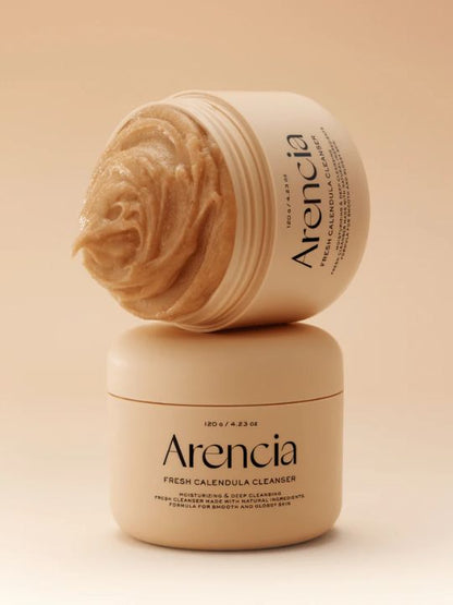 Two jars of Arencia Calendula Rice Mochi Cleanser on a beige background with one jar open.